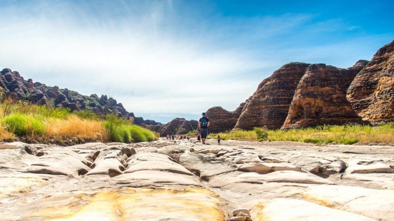 Traveller trekking across a rugged, sunlit riverbed on the 10 Day Broome to Darwin Kimberley Off Road Adventure Tours experience.
