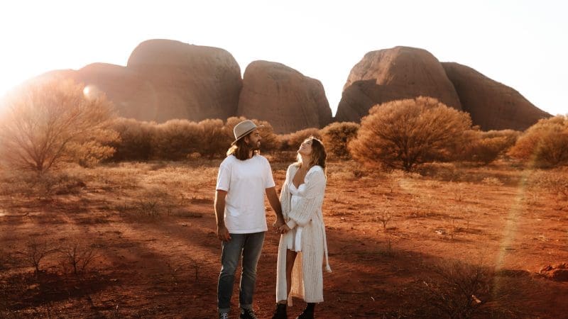 Couple holding hands at sunset in the Uluru desert, highlights of the 3 Day Uluru Kata Tjuta Kings Canyon Tour from Ayers Rock.