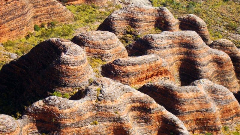 Vibrant striped sandstone domes with lush green crevices in sunlight on a 10 Day Darwin to Broome 4WD Adventure tour, Australia.