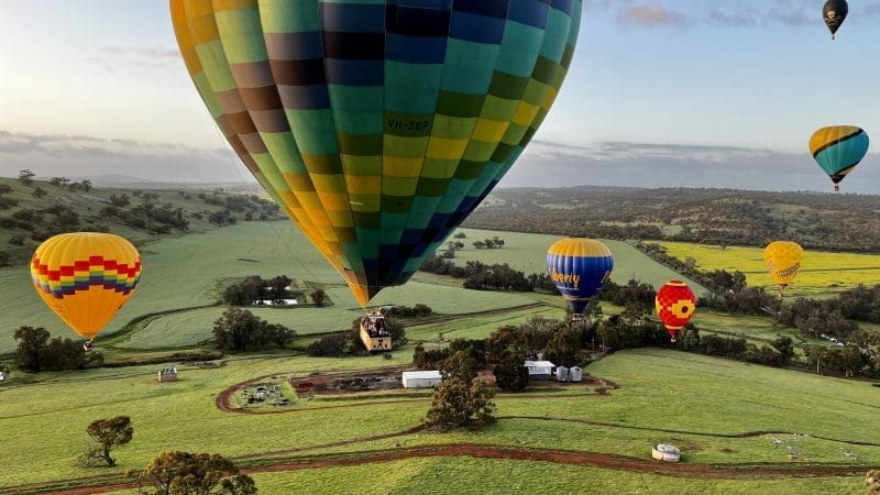 Vibrant hot air balloons soar over Avon Valley’s scenic fields at sunrise during the popular Balloon Flight With Breakfast Perth experience.